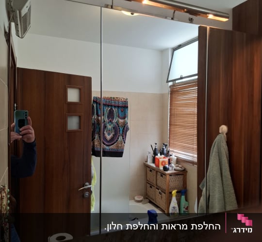 מראת קיר גדולה המותקנת מעל כיור בחדר רחצה